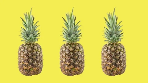Three ripe fresh pineapples rotating on yellow background Stock Footage 157117047