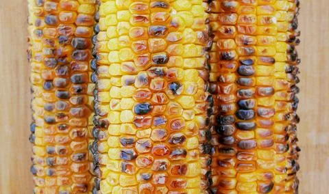 Three ripe fried corn lie side by side on a wooden background. View from abov Stock Photos