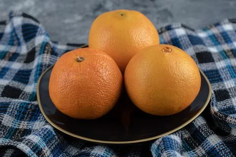 Three ripe oranges on black plate Stock Photos