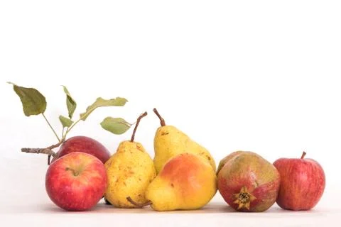 Three ripe yellow skinned pears red apples, one pomegranate, fresh organic Stock Photos