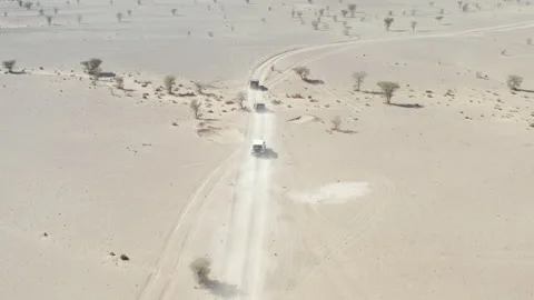 Three off-road vehicles approaching a bend on a desert track Video stock 347849362