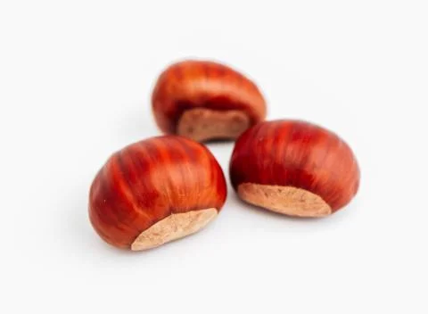 Three roasted chestnuts, close up, isolated on white background. Stock Photos
