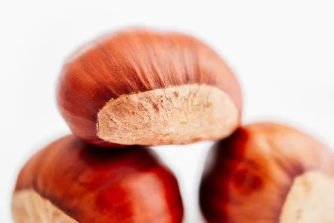 Three roasted chestnuts in a pile, isolated on white background. Brown chestn Stock Photos