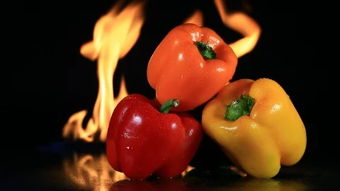 Three Roasting Bell Peppers with Fire in Background - Shallow Depth of Field Stock Footage 104078199