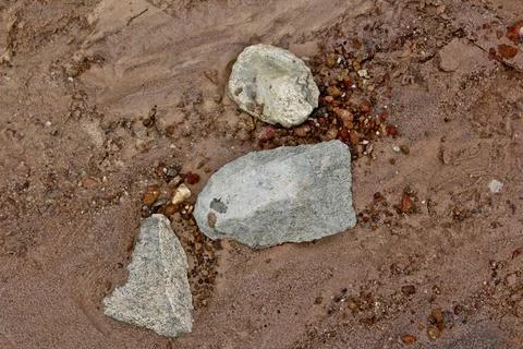 Three rocks which are hand carved tools laying in the soil Stock Photos