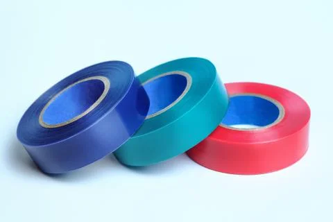 Three rolls of multicolored insulation tape. Isolated on blue background. Stock Photos