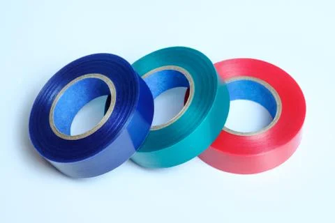 Three rolls of multicolored insulation tape. Isolated on blue background. Stock Photos