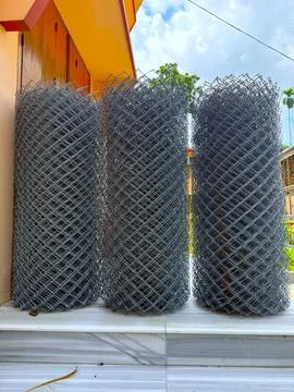 Three rolls of silver chain link fencing stand ready for installation outdoor Stock-Fotos