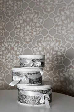 Three round celebration gift boxes with silver ribbon bows on white table. St Stock Photos