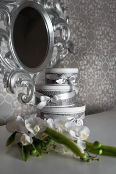 Three round celebration gift boxes with silver ribbon bows on white table and Stock Photos