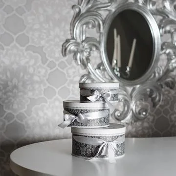 Three round celebration gift boxes with silver ribbon bows on white table. St Stock Photos