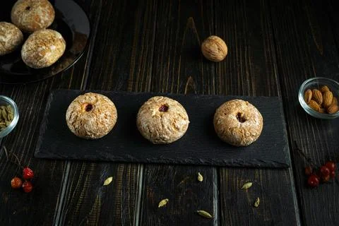 Three round cookies sit on a slate tray while more cookies rest on a black pl Stock Photos