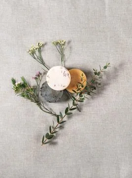 Three round handmade soaps with the twigs of flowers on the cotton background. Stock Photos