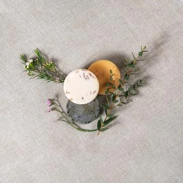 Three round handmade soaps with the twigs of flowers on the cotton background Stock Photos