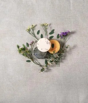 Three round handmade soaps with the twigs of flowers on the cotton background Stock Photos