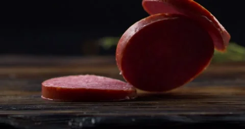 Three round pieces sausage fall on the board and lie down on top of each other Stock Footage 152102186