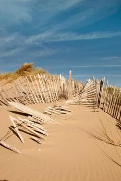 Three rows of broken fence on sand dunes vertical Stock Photos