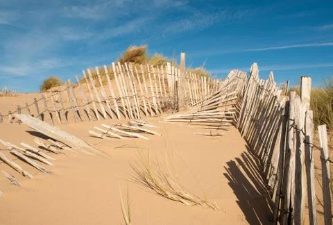 Three rows of broken fence on sand dunes horizontal wide Stock Photos