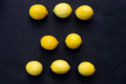 Three rows of fresh lemons lie on a black background Stock Photos