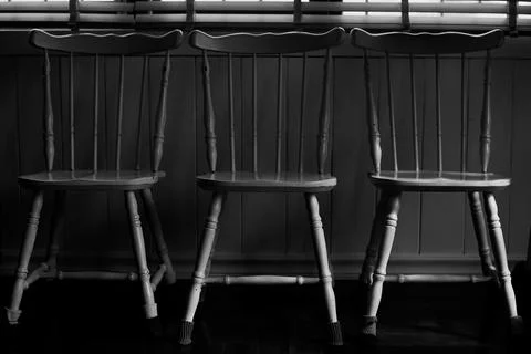 Three Rustic Wooden Chairs Lined up Near a Window With Soft Sunlight Filter.. Stock Photos