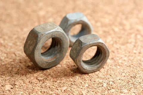 Three rusty nuts resting on a textured cork surface during daylight 스톡 사진