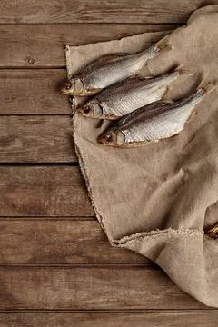 Three salted air-dried roach on sackcloth on wooden background Stock Photos