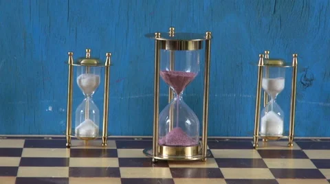 Three sand clocks with running sand placed on chess board Stock Footage 55859245