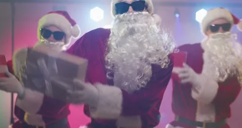 Three Santa Claus dancers grooving with gifts at a festive Christmas disco party Stock Footage 336925023