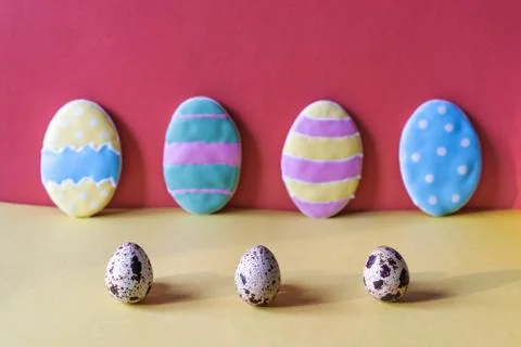 Three sawn eggs in the foreground and four cookies-eggs on a pink background Stock Photos