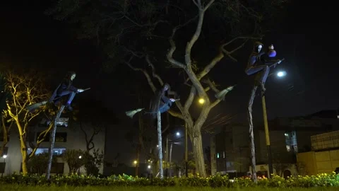 Three scary witch sculptures on straw brooms in a park at night Stock Footage 161443115