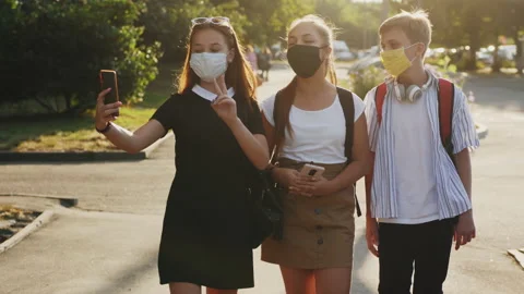 Three school-age friends are walking down the street Stock Footage 137907213