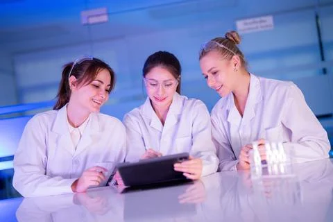 Three scientists work together in a lab while using a tablet to analyze dat.. 写真素材