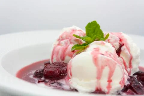 Three scoops of delicious ice cream with flowing plum jam Stock Photos