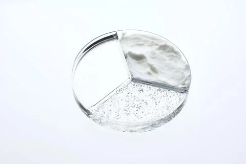 A three-section petri dish with textures of cream, cosmetic oil and serum. Stock Photos