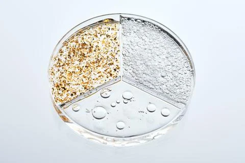 A three-section petri dish with textures of various cosmetic serums. Stock Photos