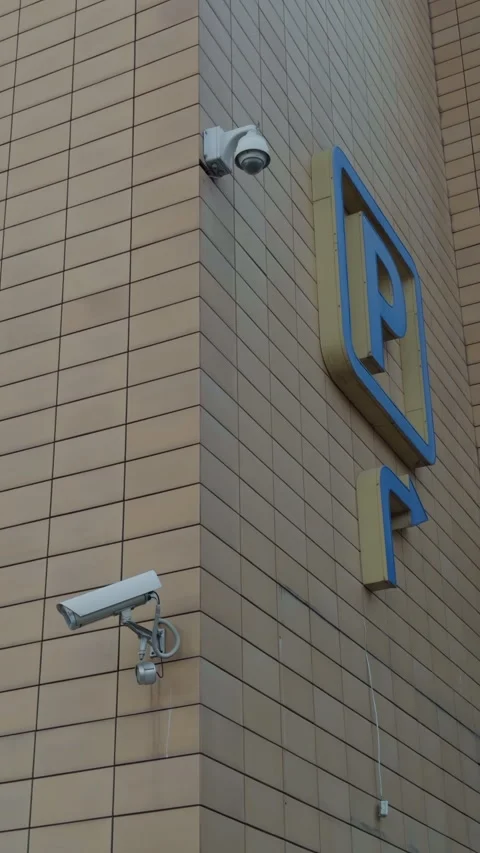 Three security cameras mounted on parking facade near large P sign, tiled Stock Footage 332735891