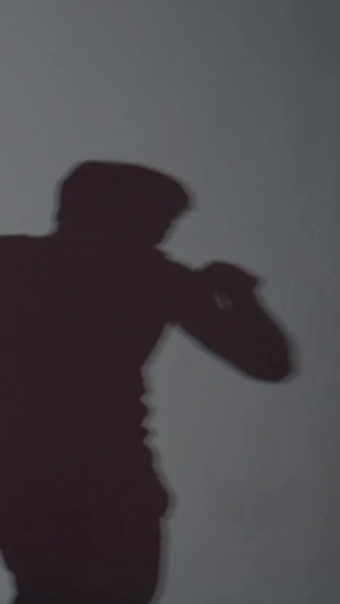 Three shadowed poses show a person using a phone, aiming, and gesturing Stock Footage 335507221