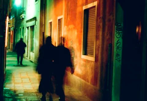 Three Shadowy People Walk at Night in Colorful Cobblestone Alley in Venice Stock-Fotos