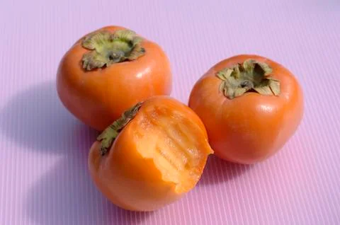 Three sharon fruits, one with a bite taken Foto stock