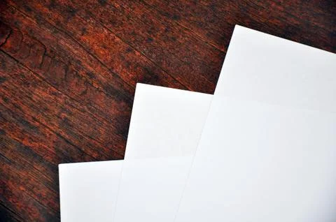Three sheets of white paper lying on a  wooden  surface Foto stock