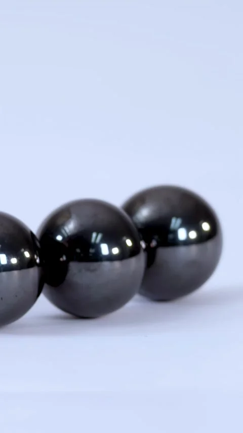 Three Shiny Magnetic Spheres Rolling and Attracting on a White Surface Stock Footage 328778577