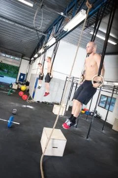 Three shirtless men exercise dips with rings Stock Photos