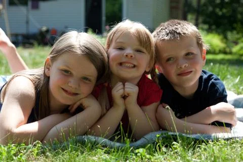 Three siblings outside in grass Stock Photos