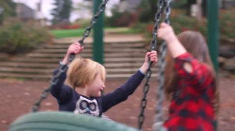 Three siblings play on a tire swing at the playground Stock-Footage 61448686