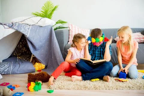 Three siblings reading a book Stock Photos