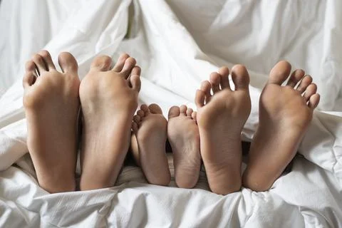 Three siblings showing their bare foot. Stock Photos