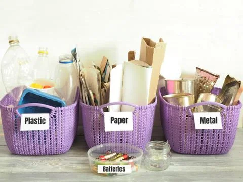 Three signed purple plastic containers with sorted garbage: plastic, paper, m Stock Photos
