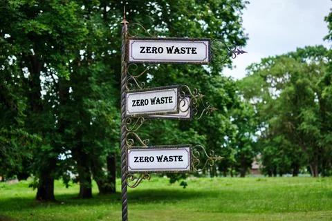 Three signs displaying Zero Waste stand tall in a lush green park, encouraging Stock Photos