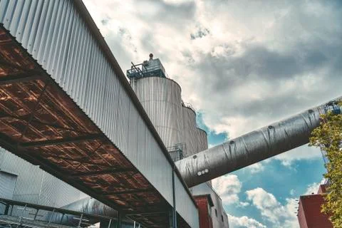 Three silos and a large pipe of a factory with dramatic sky Stock Photos