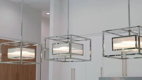 Three silver decorative contemporary led chandeliers of square shape hanging on Stock Footage 245770673